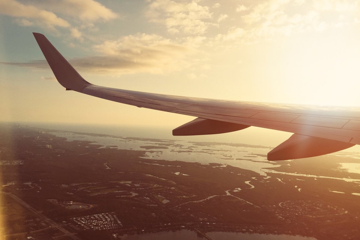 Aussicht aus dem Fenster eines Flugzeuges auf eine Landschaft bei Sonnenuntergang.