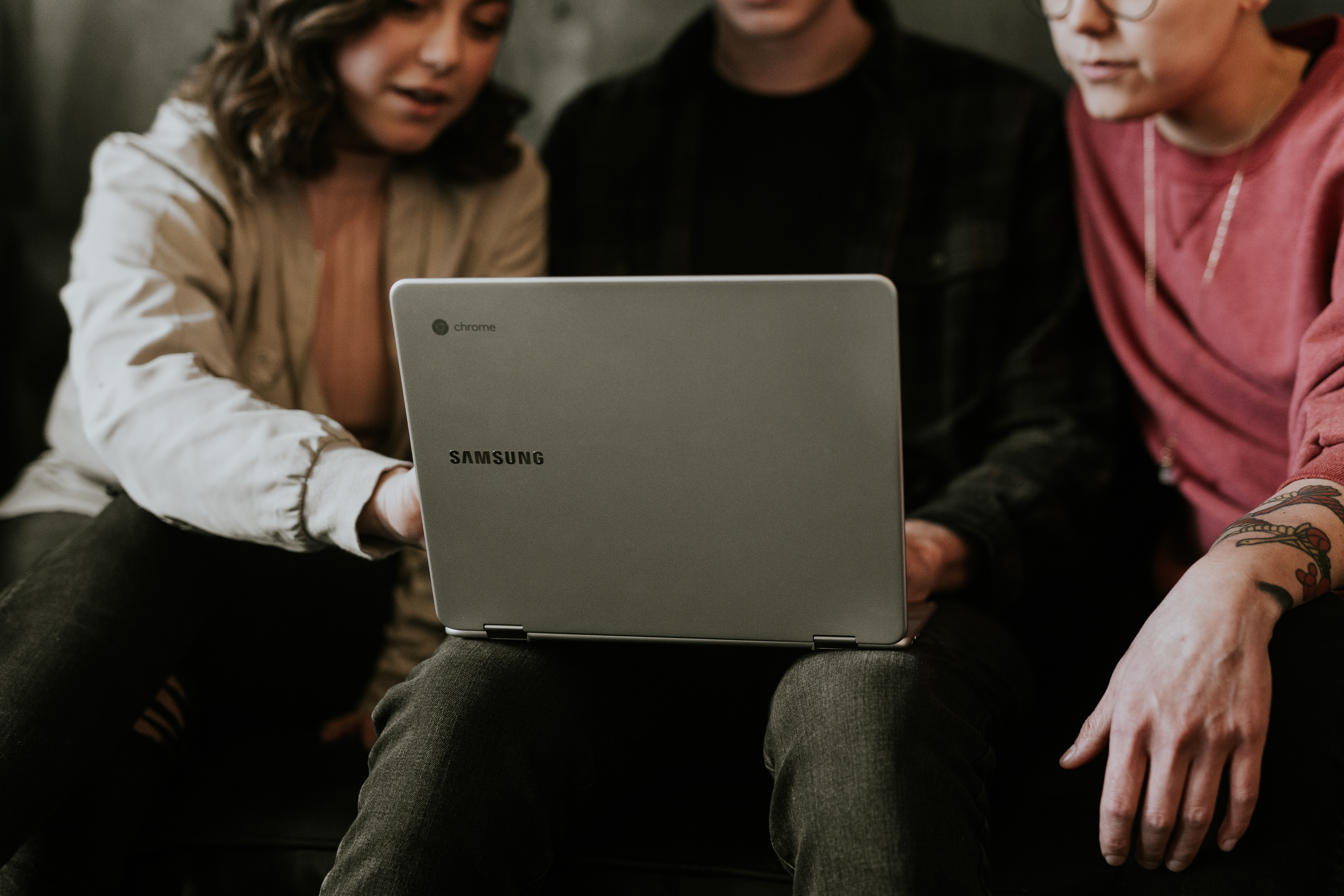 Studierende besprechen sich und zeigen auf einem Laptop.